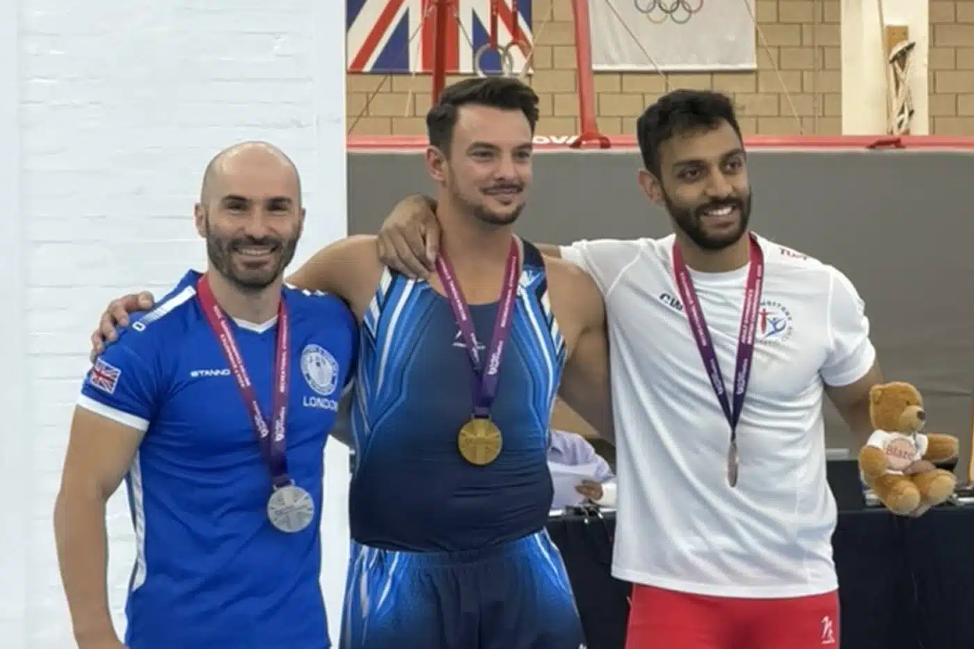 Three adult gymnasts on the podium with medals at the 2026 Adult Gymnastics British Championships