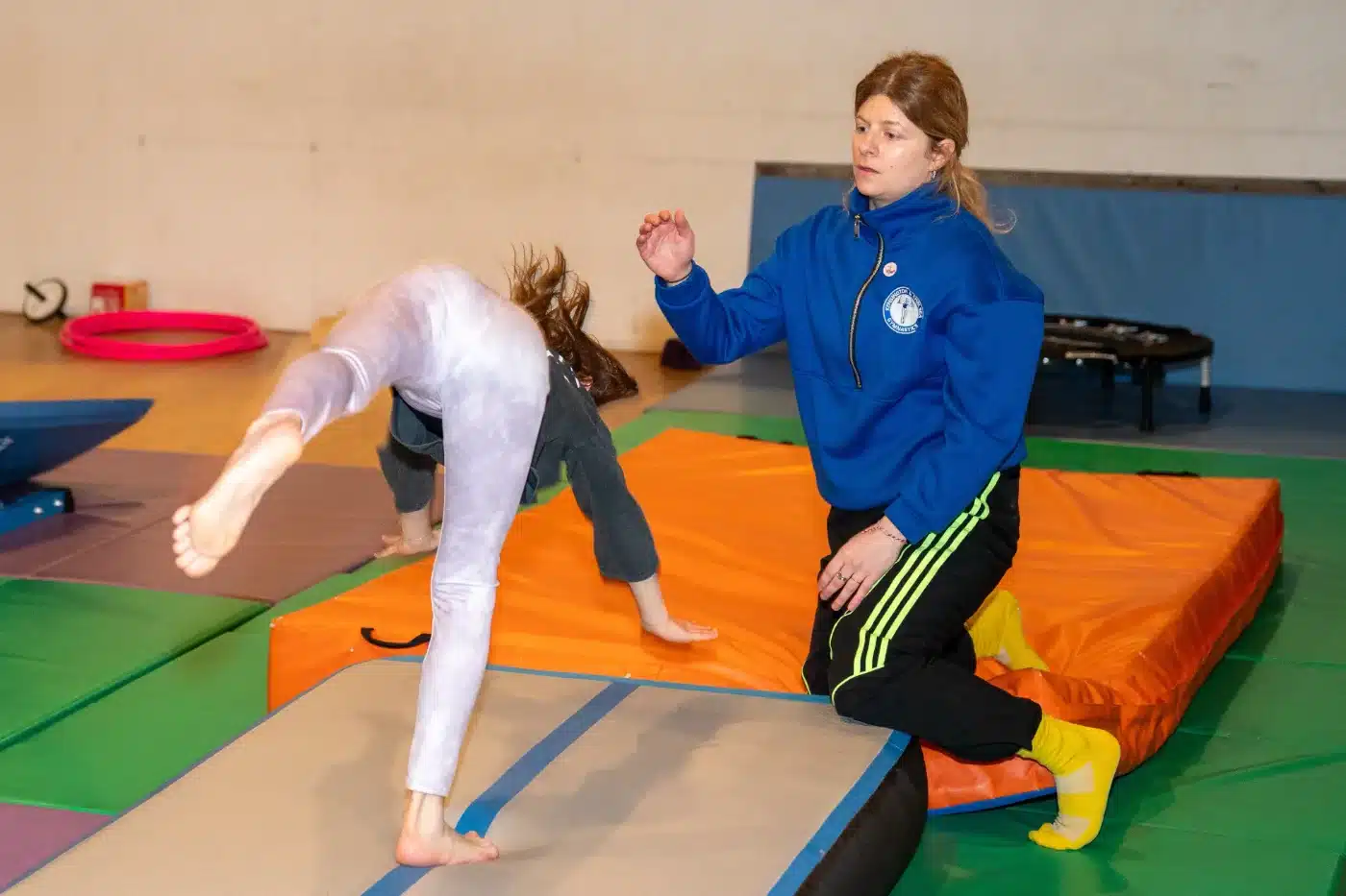 Coach Daniel spotting a gymnast during a supported gymnastics skill at KCGA