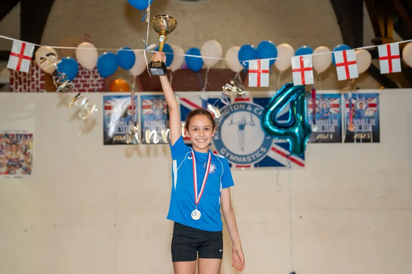 Sofia lifting her Gymnast of the Year trophy during KCGA Annual Performance 2026