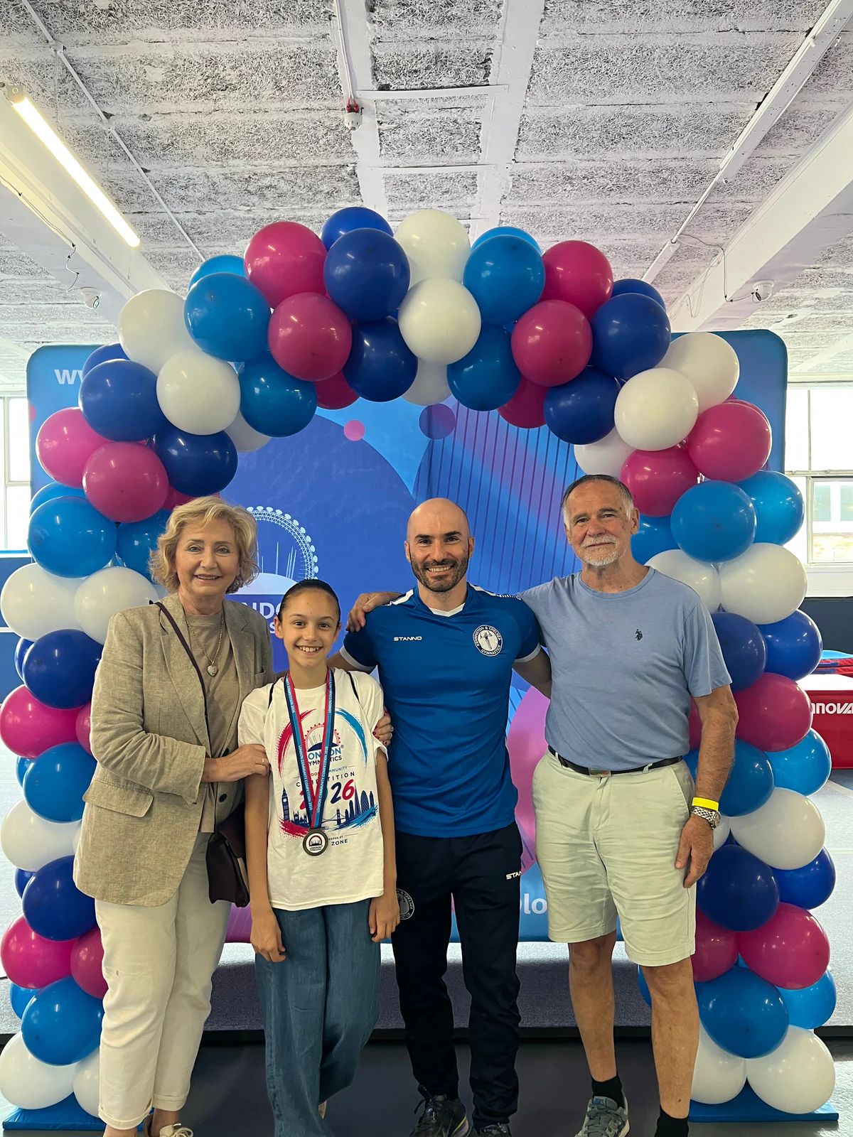 A young gymnast celebrating with her family and coach after the London Community Competition.